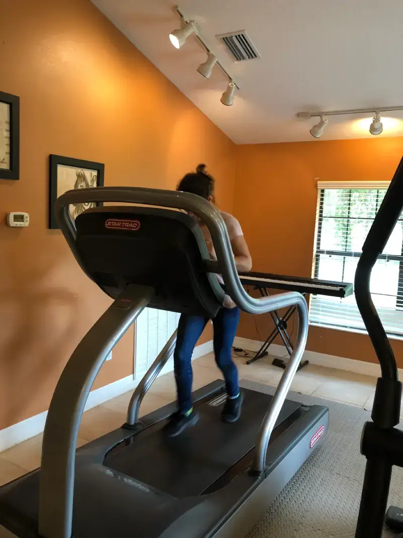 A woman is walking on the treadmill in her home gym.