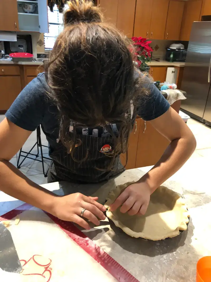 A woman is making some kind of pie