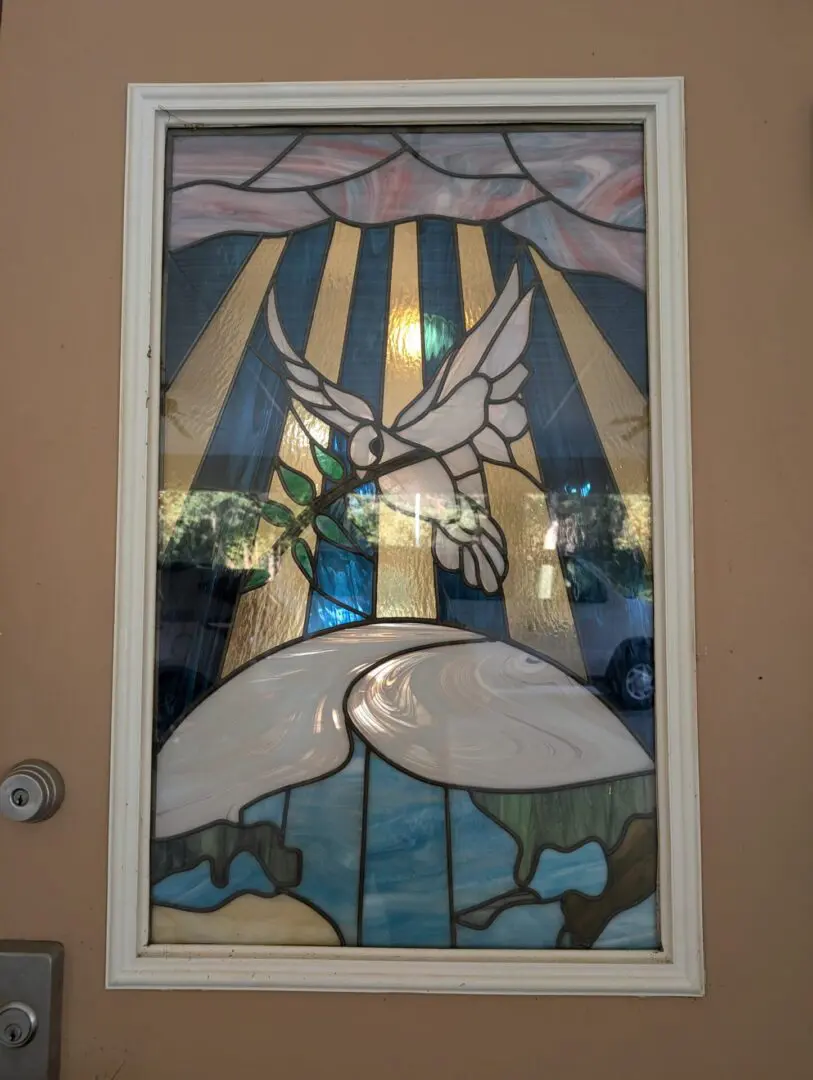 A stained glass window with a bird and sun.