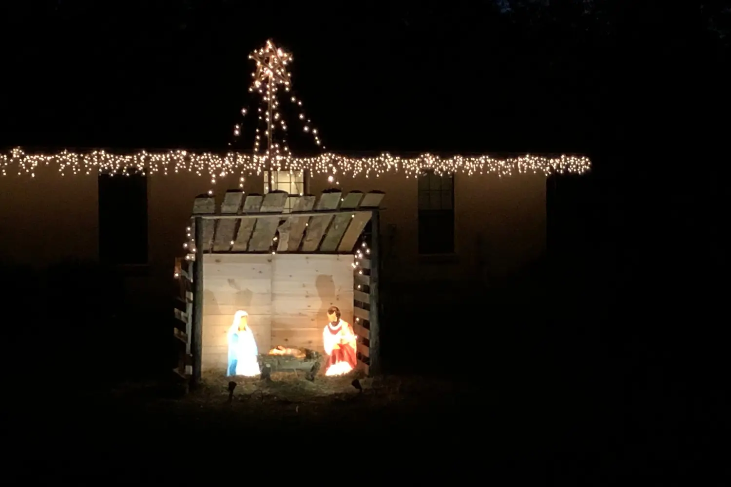 A nativity scene with lights on the roof.