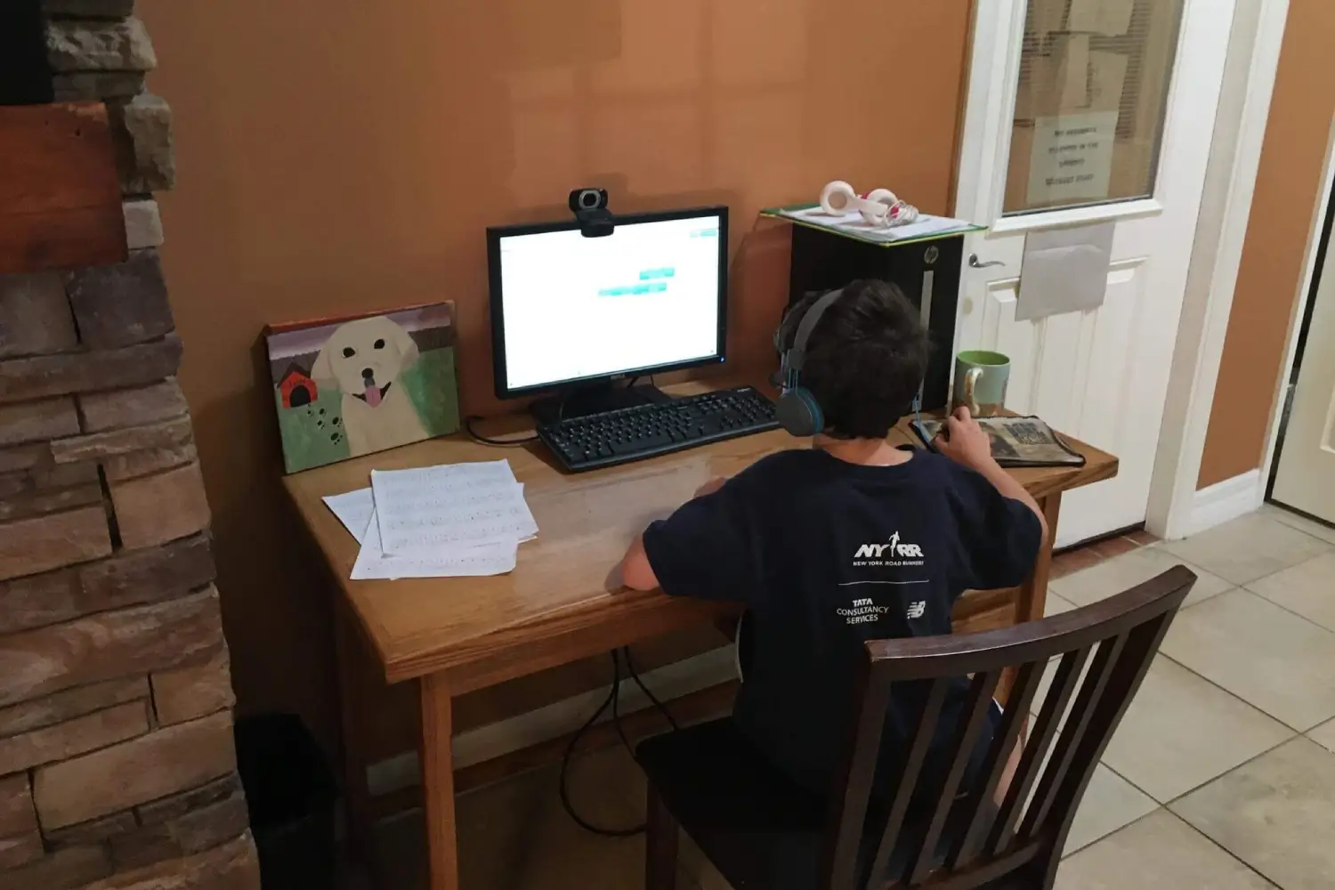 A boy sitting at his desk with headphones on.