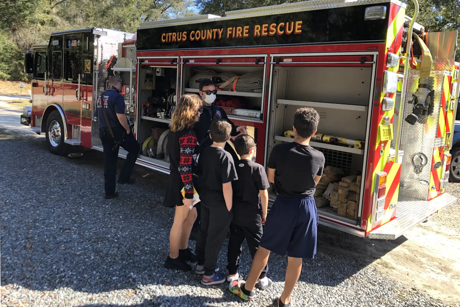 A group of people standing around an open fire truck.