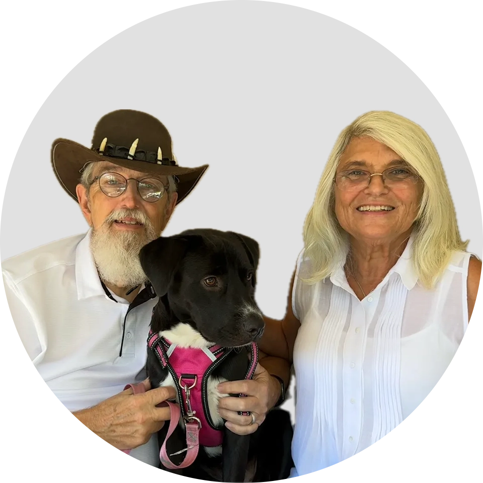 A man and woman holding a dog in front of a white background.