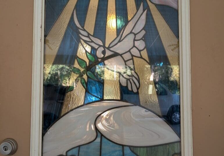 A stained glass window with a bird and sun.